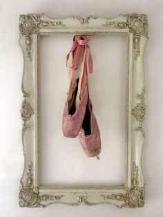 a pair of ballet shoes hanging in a frame