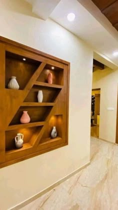 a wall mounted shelf filled with vases on top of a white wall next to a doorway