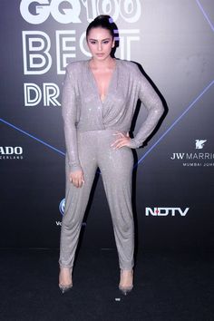 an image of a woman posing for the camera in silver jumpsuits and heels