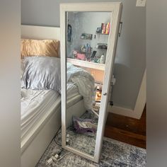 a mirror that is in the corner of a room with a bed and bookshelf