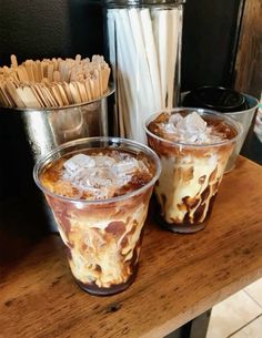 two glasses filled with ice cream sitting on top of a wooden table next to some straws