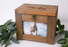 a small wooden box with a photo on it and some green leaves in the background