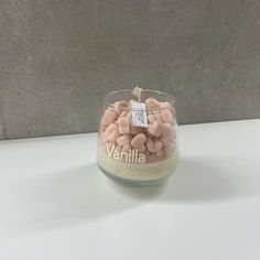 a glass jar filled with candies sitting on top of a white table next to a gray wall