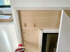 a hand holding a bottle of wood glue next to a wooden door and window frame