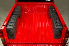 the back end of a red pick up truck with speakers on it's bed