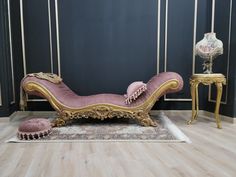 a pink chaise lounge sitting on top of a wooden floor next to a table