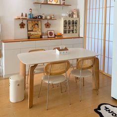 a white table and chairs in a room with wood flooring, shelves on the wall