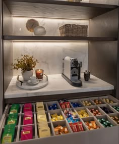 a shelf filled with lots of different types of chocolates and coffee cups on top of it