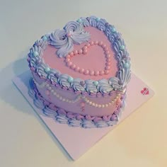 a pink heart shaped cake with pearls and beads on the top is sitting on a card