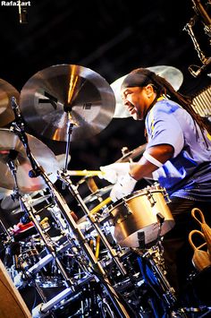 a man with dreadlocks playing drums on stage