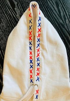 a white hat with red and blue crosses on it sitting on top of a wooden floor