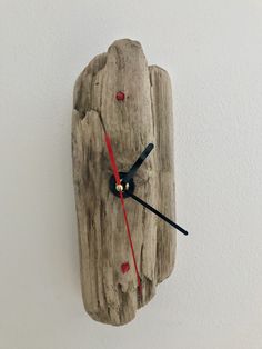 a clock made out of drift wood with red hands and numbers on the face is shown