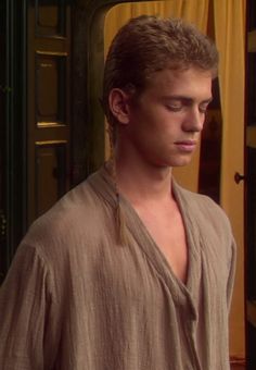 the young man is looking down at his cell phone while standing in front of an open door