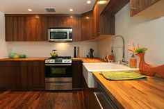 a kitchen with wooden floors and white walls, has stainless steel appliances and wood counter tops