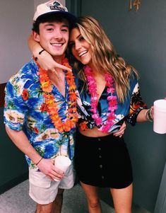 a man and woman posing for a photo in front of a wall with flowers on it