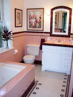 a bathroom with pink tiles and white fixtures, including a bathtub, sink, toilet and mirror