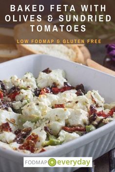 baked feta with olives and sundried tomatoes in a white casserole dish