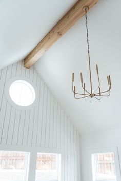 a chandelier hanging from the ceiling in a room with white walls and wood beams