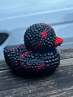 two black and red beads sitting on top of a wooden table next to a white car