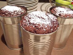 three tins filled with brownies sitting on top of a table next to plates