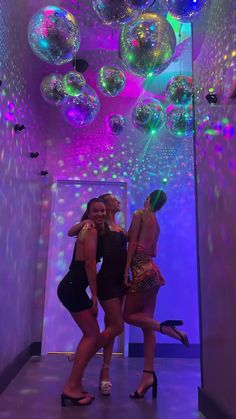 three women are posing in front of disco balls