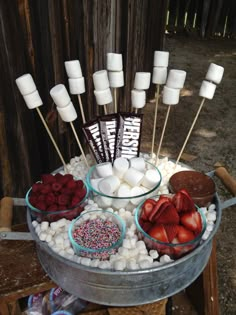 a bucket filled with marshmallows, strawberries, and chocolate on sticks