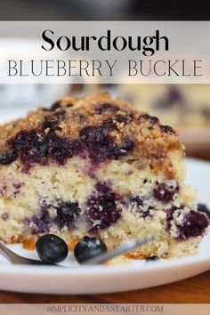 a piece of blueberry crumb cake on a white plate with a fork next to it