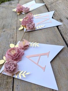 some paper flowers are laying on top of a wooden table with gold foil and pink roses