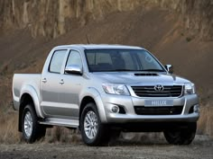 a silver truck is parked in front of a mountain