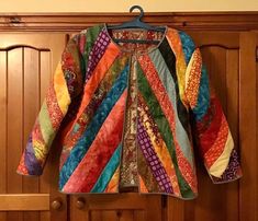 a multicolored jacket hanging on a coat rack in front of a wooden door