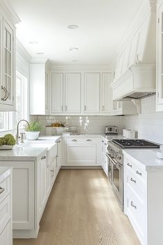 a kitchen with white cabinets and wood floors