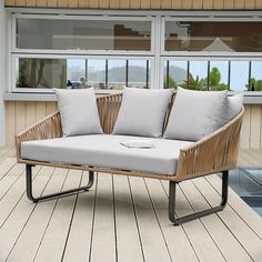 a couch sitting on top of a wooden floor next to a swimming pool in front of a window