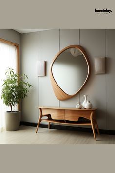 a wooden table sitting under a round mirror next to a potted plant