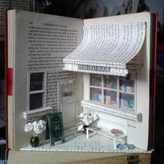 an open book with a miniature house made out of books and pages that are cut in half