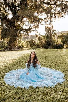 a woman in a blue dress sitting on the grass