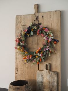 an old wooden board with a wreath on it next to a cutting board and knife