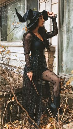 a woman in a witch costume posing for the camera with her hat on and legs crossed