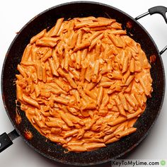 a skillet filled with pasta on top of a white table