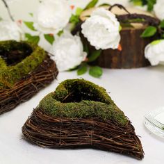 moss covered shoes sitting on top of a table next to white flowers and greenery