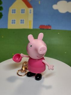 a pink pig keychain with a house in the background and a red car