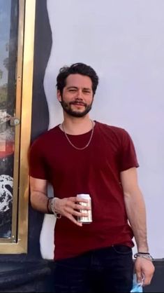 a man standing next to a painting holding a can of beer in his right hand