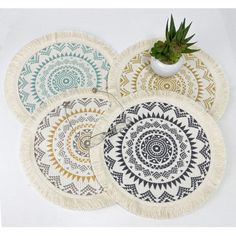 four woven coasters with designs on them and a potted plant in the middle