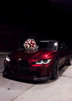 a red car parked in front of a building with a wreath on it's hood