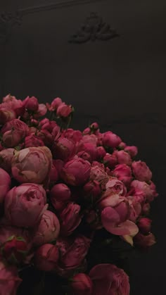 a bunch of pink flowers sitting on top of a black countertop next to a wall