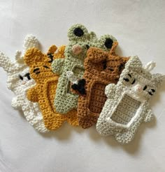 four crocheted teddy bears sitting next to each other on top of a white sheet