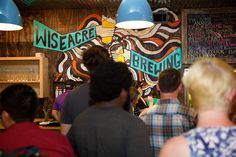 a group of people standing in front of a bar with signs on the wall behind them