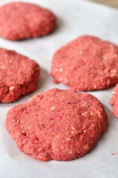 some red cookies are sitting on a sheet of wax paper and ready to be baked