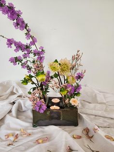 an arrangement of flowers and candles on a bed