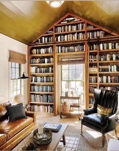 a living room filled with lots of furniture and bookshelves next to a window