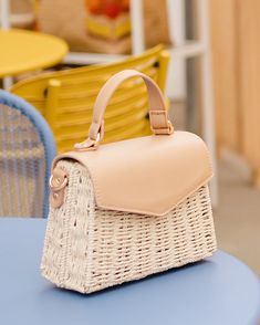 a wicker purse sitting on top of a blue table next to yellow and white chairs